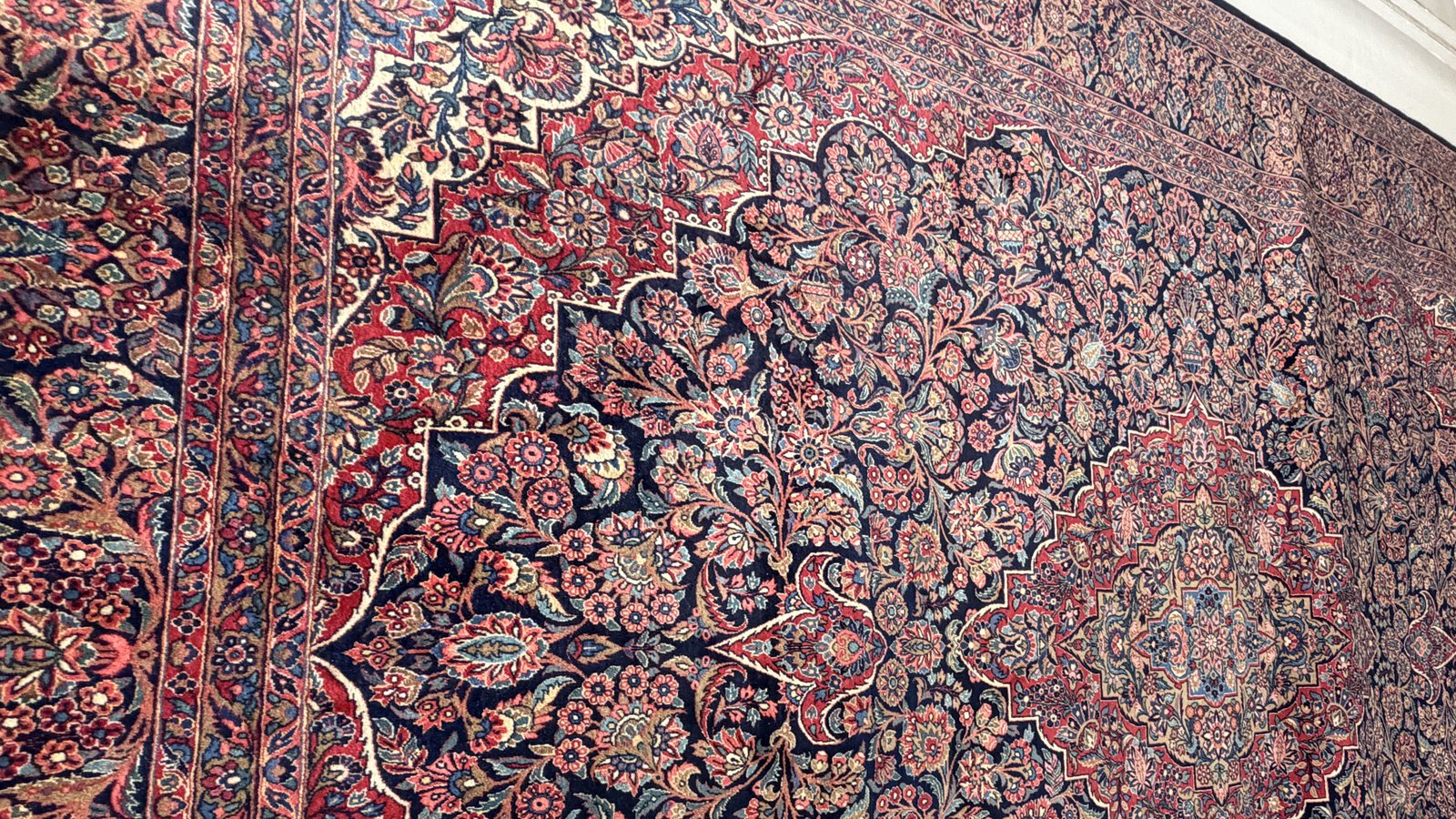 A washed hand-knotted rug photographed flat, rolled and ready to go back out for delivery